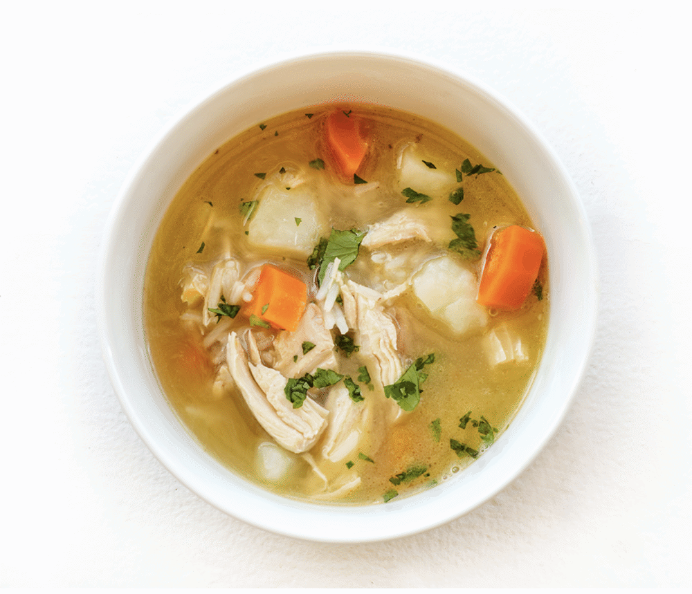 Steaming bowl of Epicured's Low FODMAP Chicken & Rice Soup with tender chicken pieces, basmati rice, and fresh herbs