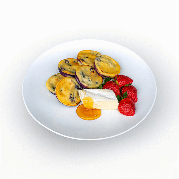 Fluffy buckwheat pancakes topped with fresh strawberries, a side of creamy brie, and a drizzle of maple syrup.