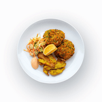 Epicured's Montauk Crab Cakes served with coleslaw, lemon-paprika aioli, and smashed potatoes on a white plate.